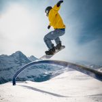 man in yellow jacket and black pants riding on black skateboard during daytime